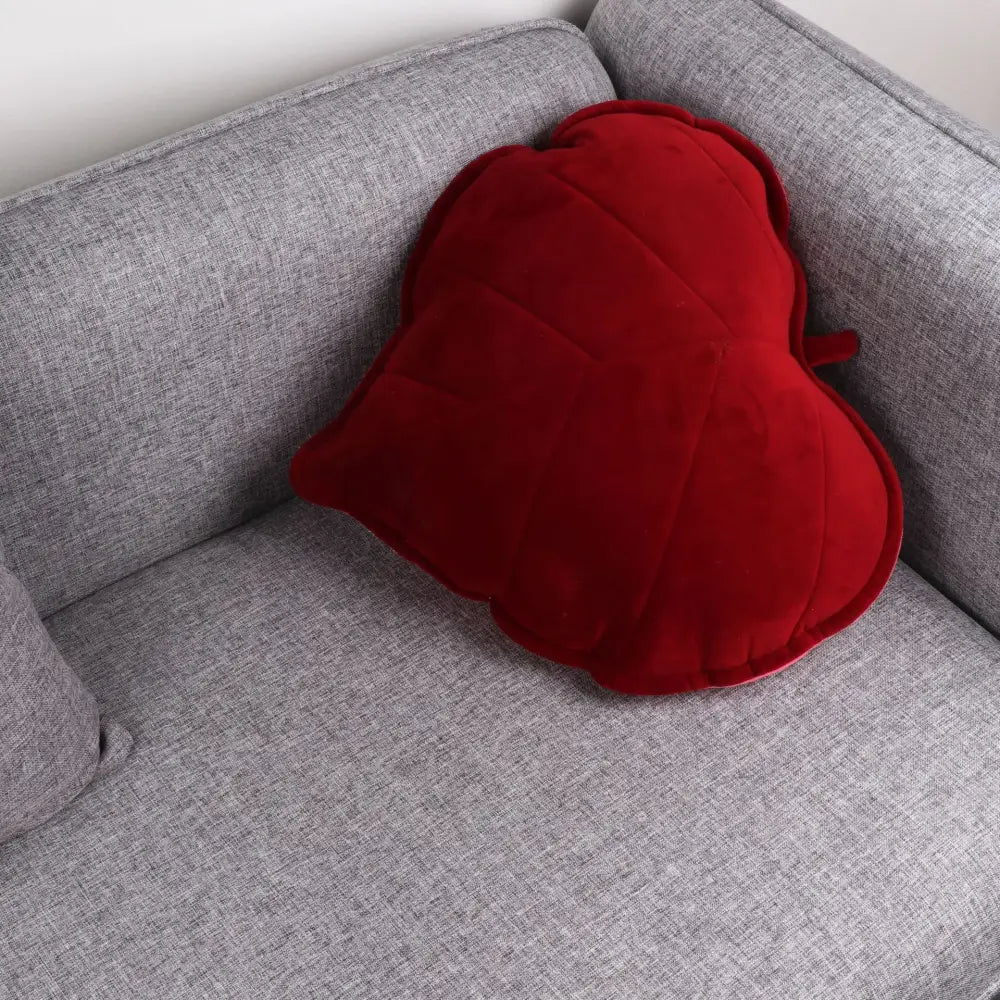 A plush deep red heart cushion with quilted texture on gray sofa complements decorbites 3d leaf throw pillow decor
