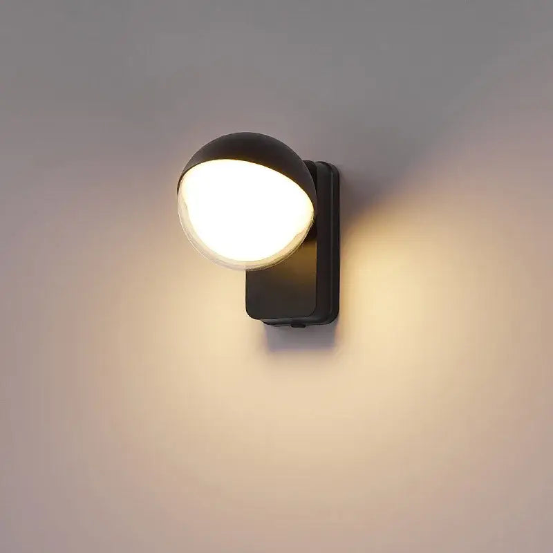 Modern black spherical wall lamp with motion sensor emitting warm diffused glow for porch lighting