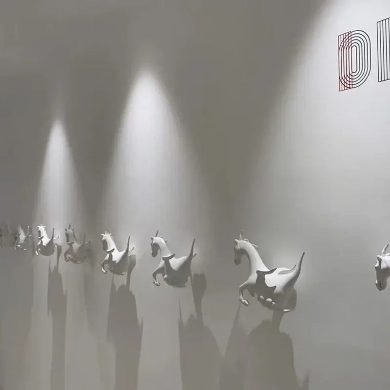 A row of white ceramic horse sculptures illuminated by a modern white and black 25w dimmable led spotlight track light