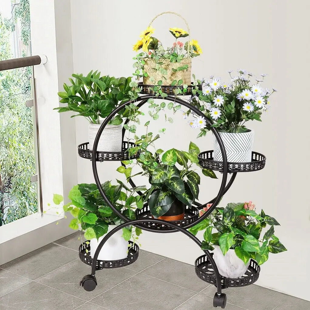 Black wrought iron decorbites plant stand shelf with decorative perforated tiers and caster wheels holding six pots