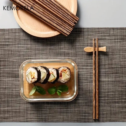 Set of natural wooden chopsticks with fish-shaped rest beside sushi container enhancing dining experience
