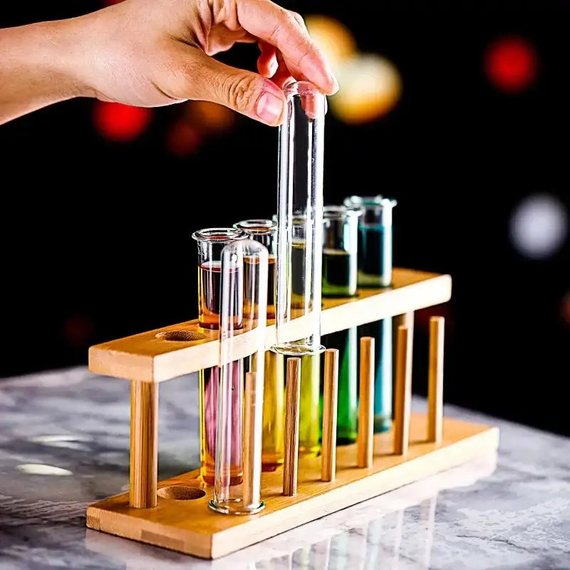 A wooden DecorBites™ test tube cocktail glass rack holding six colorful glass test tube cocktail glasses