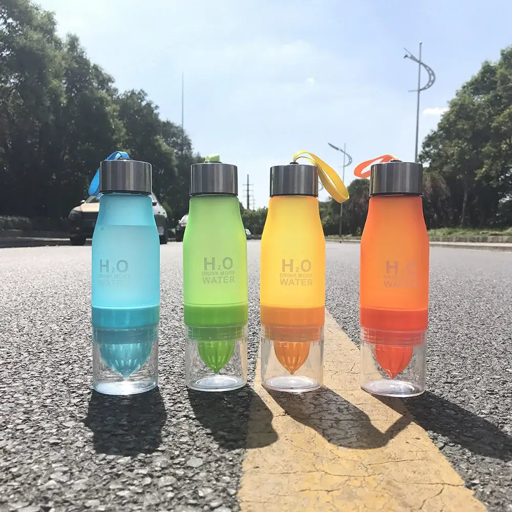 Four colorful translucent DecorBites 650ml infuser water bottles with silver caps and built-in citrus juicers for refreshing hydration