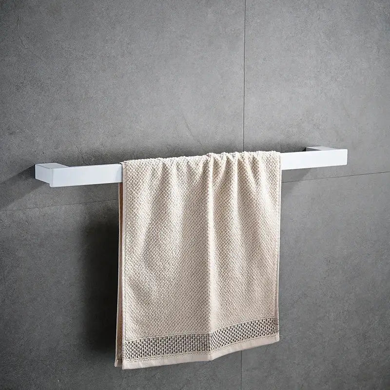 A cream-colored textured towel with mesh trim hangs on a white wall-mounted rack in DecorBites bathroom hardware set
