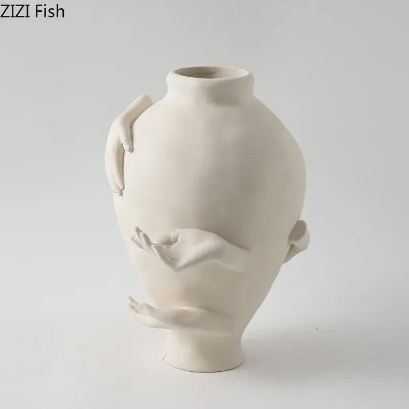 Cream-colored decorbites abstract art ceramic vase with sculpted hands wrapping its rounded body for desk decoration