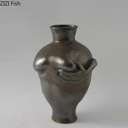 A sleek metallic gray decorbites abstract art ceramic vase featuring a sculpted torso and hand holding a small object