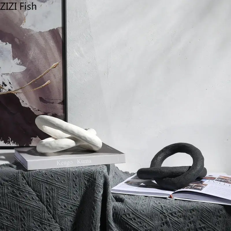 White decorbites abstract ceramic knot sculpture with smooth rounded forms resting on a book for room aesthetic decor