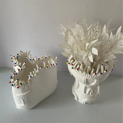 White ceramic vase shaped like human head with colorful pins featuring decorbites abstract coral flower pot design