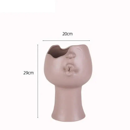 A matte blush pink abstract face ceramic planter by decorbites shaped as a stylized head with an open mouth planting hole