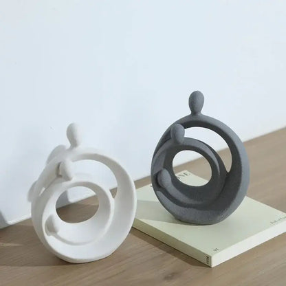 Two minimalist white and gray ceramic figurines with circular rings in decorbites abstract family sculpture set
