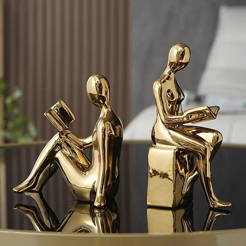 Two golden glossy decorbites abstract figure bookend set depicting seated human forms reading books for stylish decor