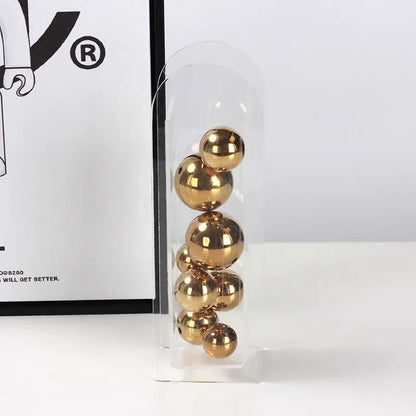 A clear acrylic ball vase stack with polished gold-colored metallic spheres for home decoration by decorbites