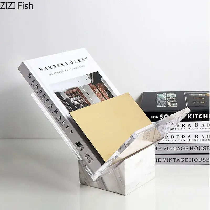 Clear acrylic bookshelf with marble base holding a gold notebook and white book for modern home decor organization