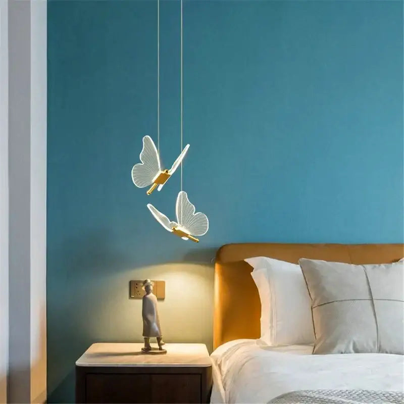 DecorBites™ acrylic butterfly led pendant light with translucent white wings and gold centers against teal wall