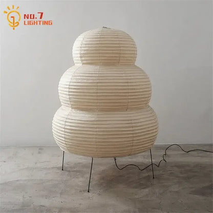 Cream-colored akari noguchi table lamp with tiered rice paper shade and slender metal legs for elegant lighting