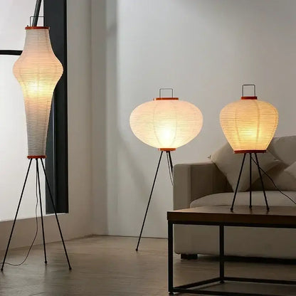 Three elegant decorbites™ akari rice paper floor lamps with black metal tripod bases and warm glowing interiors