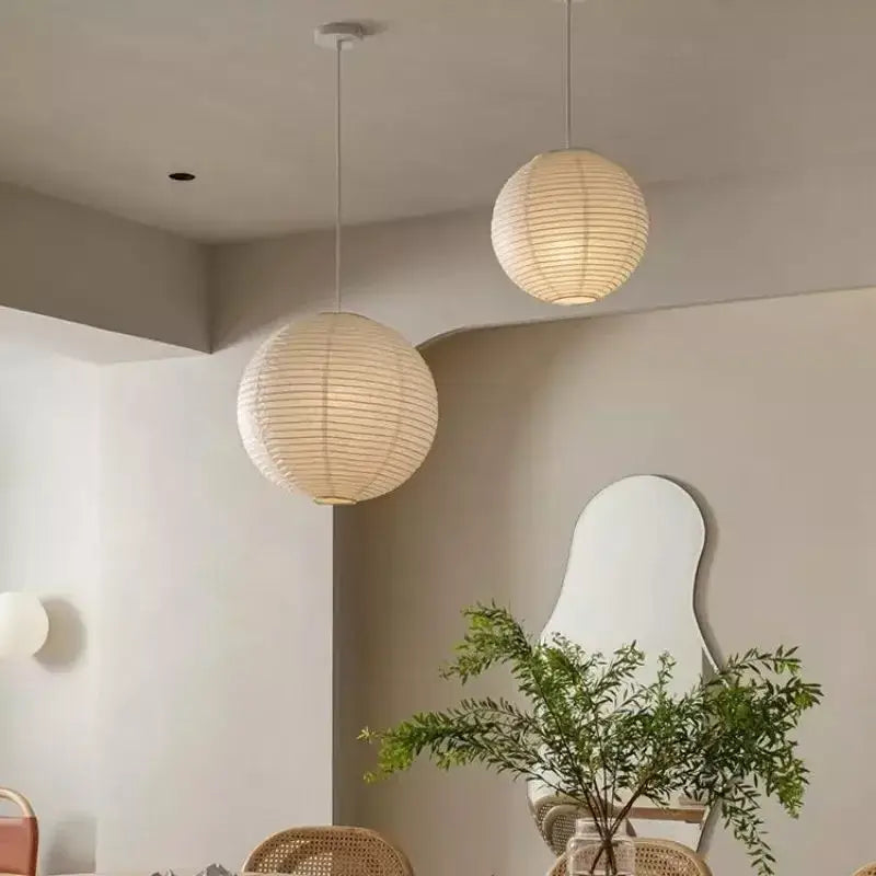 Two off-white spherical pendant lights made of akari vintage rice paper hang from the ceiling by thin cords