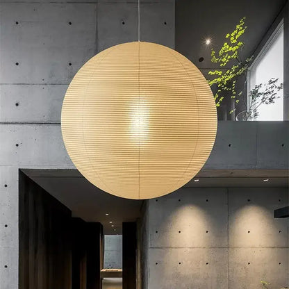 A warm spherical akari vintage rice pendant light made of rice paper with horizontal ribbing hangs from the ceiling