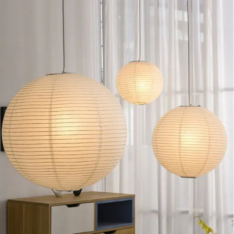 Three warm glowing spherical pendant lights with vertical ribbed texture made of rice paper akari vintage rice style