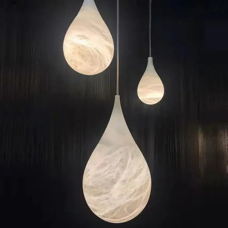 Three alabaster pendant lights with a swirling white and beige marble finish by decorbites for living room lighting