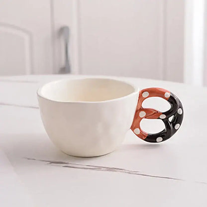 White ceramic alkali water biscuit mug with playful pretzel-shaped handle in black orange and white polka dots