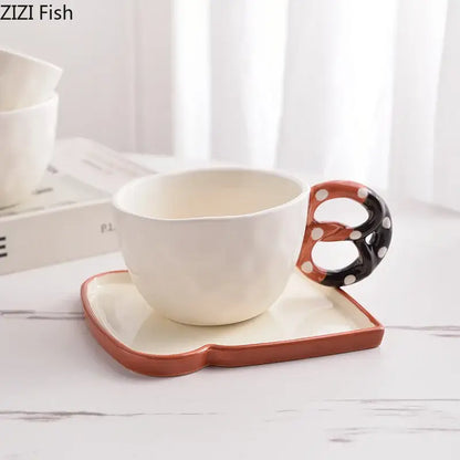 White ceramic DecorBites alkali water biscuit mug with black orange pretzel handle and matching rectangular saucer