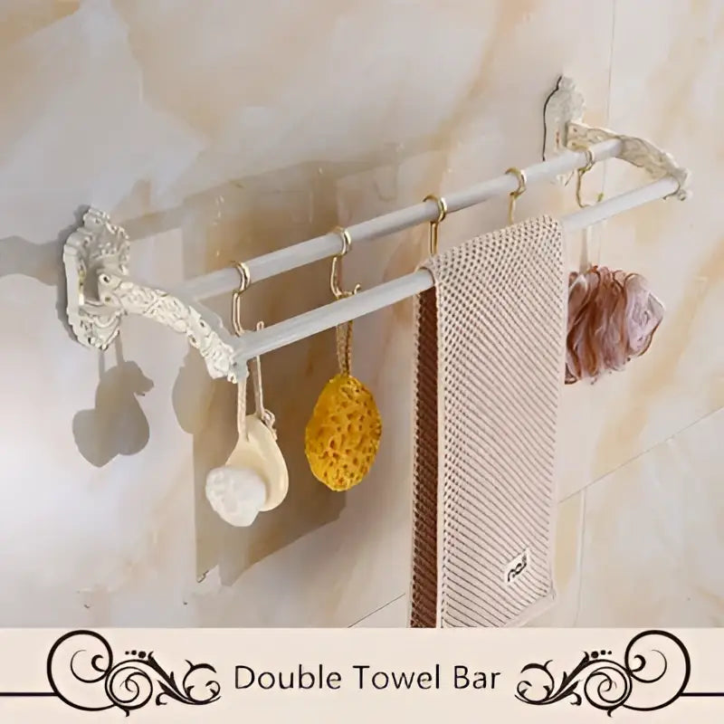 Decorbites™ aluminum bath hardware set with white ornate double towel bar and gold-toned hooks holding towel and loofah