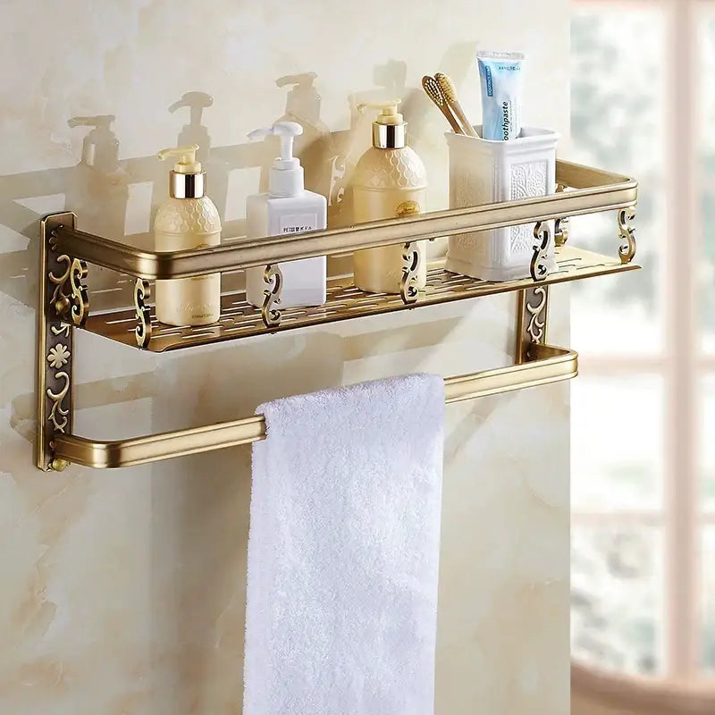 Gold-toned aluminum DecorBites™ bathroom corner shelf with ornate floral detailing holding toiletries and a matching towel bar