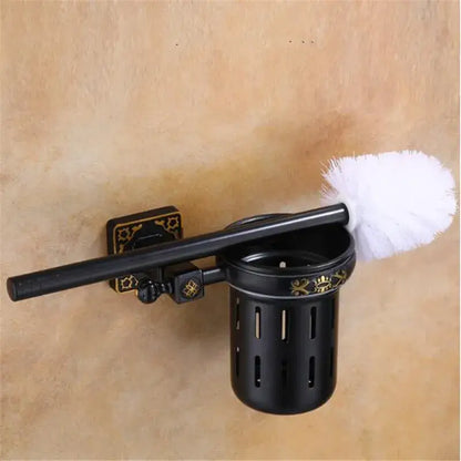 Decorbites aluminum carved black metal toilet brush holder with gold floral accents holding white bristle brush