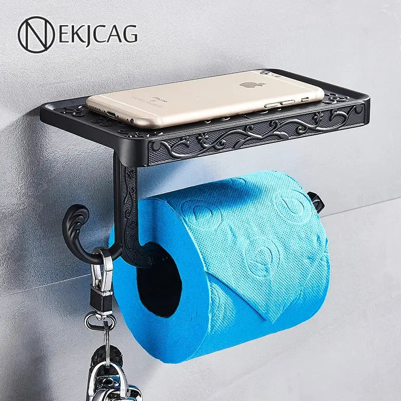 Black ornate aluminum toilet paper holder by DecorBites with a sleek phone rack shelf and hook holding keys
