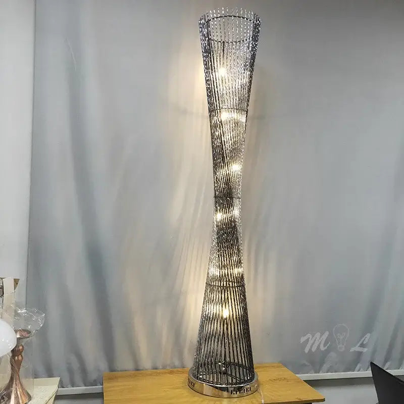 Tall slender decorbites aluminum tower floor lamp with twisted metallic frame and warm LED lights for living room use