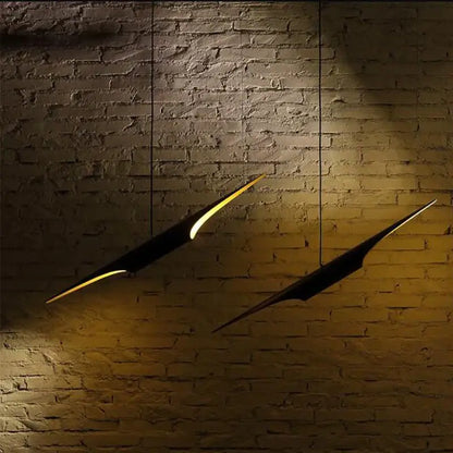 Two black decorbites aluminum tube pendant lights with glowing yellow edges hang on a textured brick wall