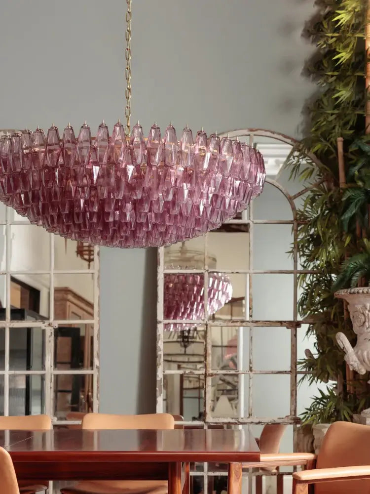 A glamorous amber glass ceiling chandelier with cascading teardrop design hanging from a gold chain for dining table