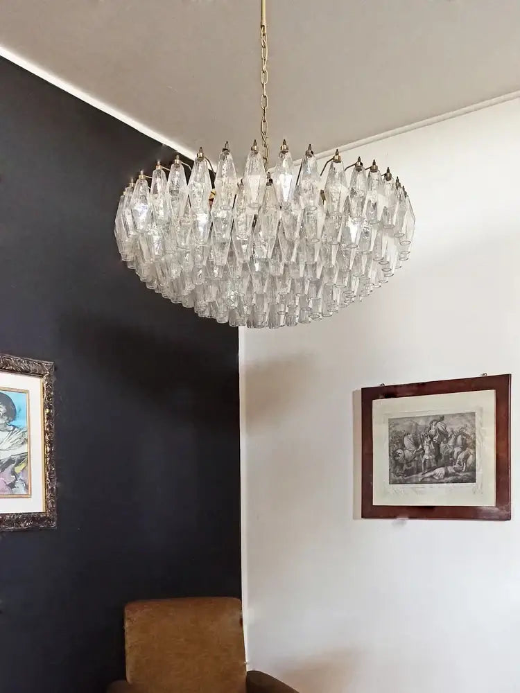 A clear faceted crystal glass ceiling chandelier with gold metal frame hanging from ceiling for dining table