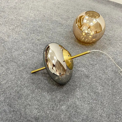 Decorbites amber glass chandelier featuring two spherical lampshades in reflective silver and warm amber hues on gold stems