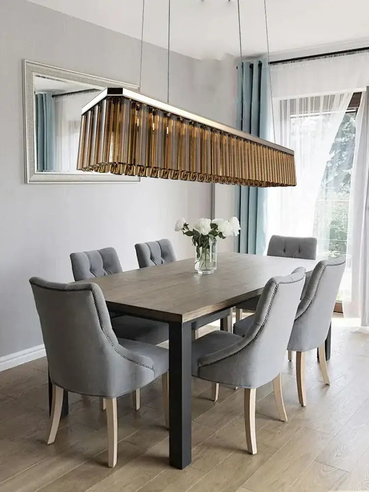 DecorBites™ amber glass chandelier with gold-toned vertically slatted glass design hanging above dining table