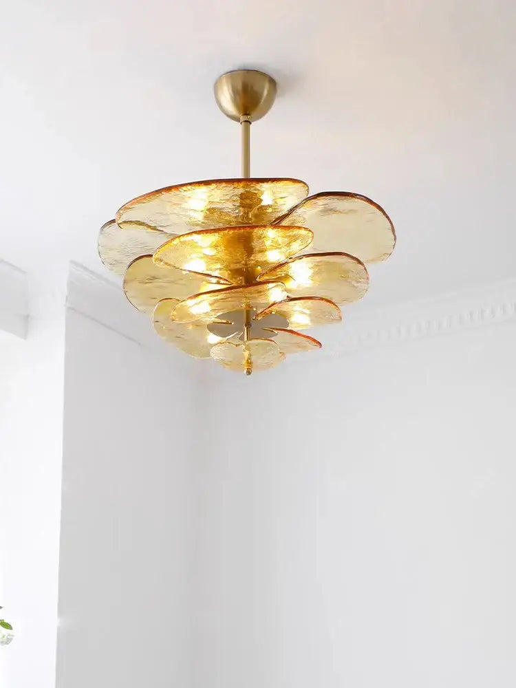 A tiered amber glass chandelier with brass finish and layered petal-like shades for elegant living space lighting
