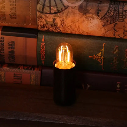 A warm white 2200k decorbites amber glass led bulb with vintage edison filament on a sleek black base