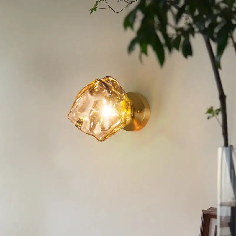 Golden brass wall lights with a decorbites amber glass led shade shaped like an irregular faceted crystal