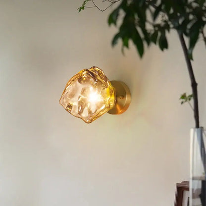 Golden brass wall lights with a decorbites amber glass led shade shaped like an irregular faceted crystal