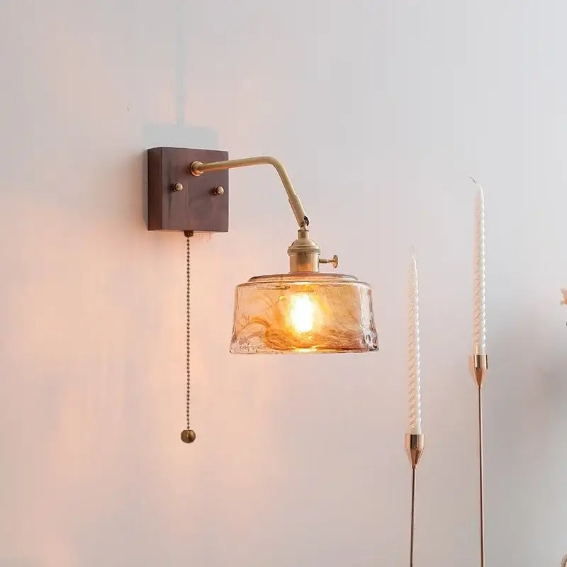 A decorbites amber glass led wall sconce with warm amber glass shade and brass-finished metal arm and base