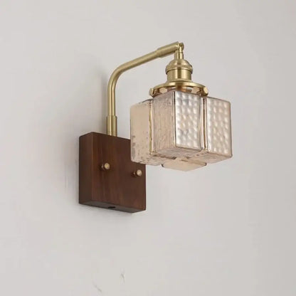 Decorbites amber glass led wall sconce with brass finish and walnut wood base mounted on dark wood background