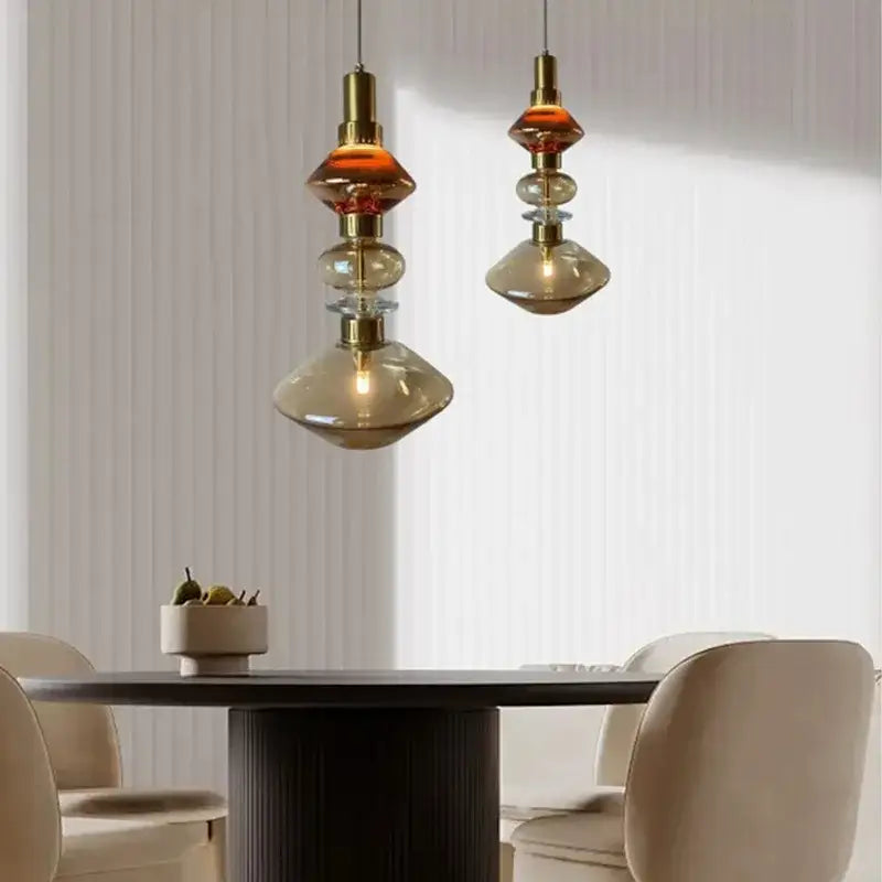 Two elegant decorbites amber glass pendant lights with brass accents hang above a dining table in vintage style