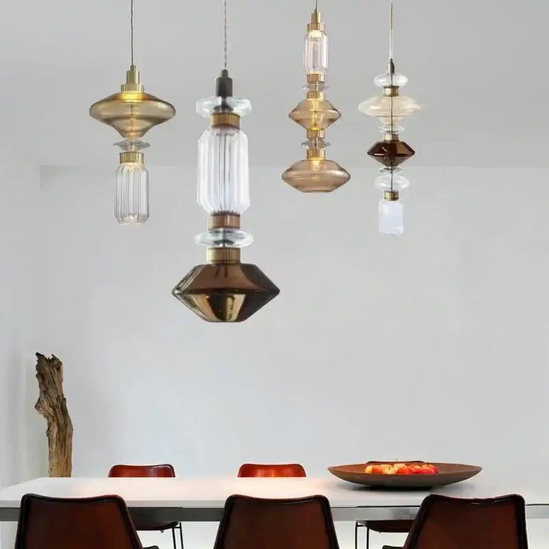 A collection of decorbites amber glass pendant lights with brass accents in stacked geometric shapes for hotel bedrooms