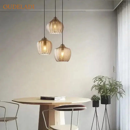 Three decorbites amber glass pendant lights with textured amber glass shades and black cords for kitchen lighting