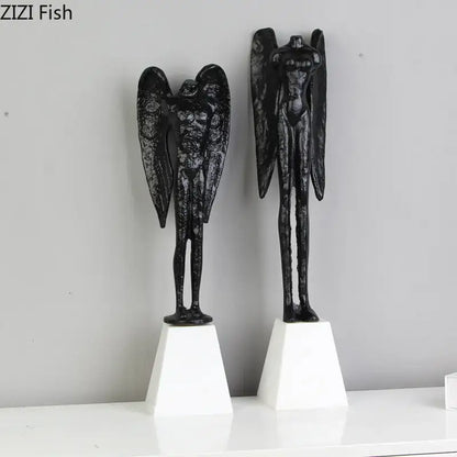 Black angel abstract figures sculpture cast iron with textured wings on white pedestals for home decor by DecorBites