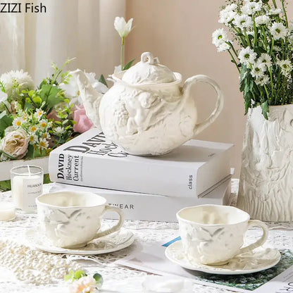 White ceramic angel relief ceramic teapot with intricate cherub and foliage detailing on stacked books from decorbites relief ceramic tableware set
