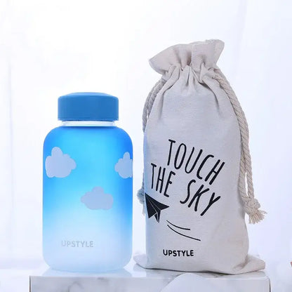 Blue gradient glass water bottle with white cloud decals and a matching blue lid by DecorBites for outdoor use