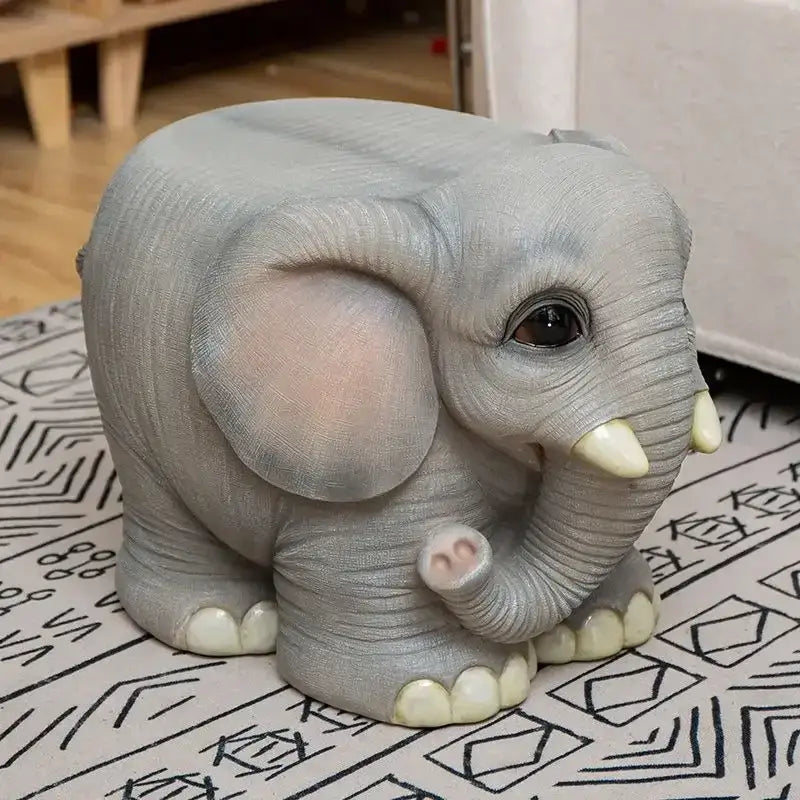 Gray elephant resin sculpture footstool seat with detailed textured skin and pink ears on a patterned surface