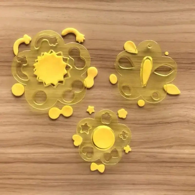 Yellow translucent plastic animal shape sushi rice mold set with intricate flower designs and small matching pieces scattered